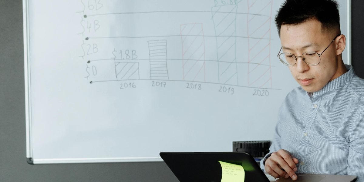 Osoba planująca strategię finansową i optymalizację kosztów, zapisująca pomysły na tablicy.